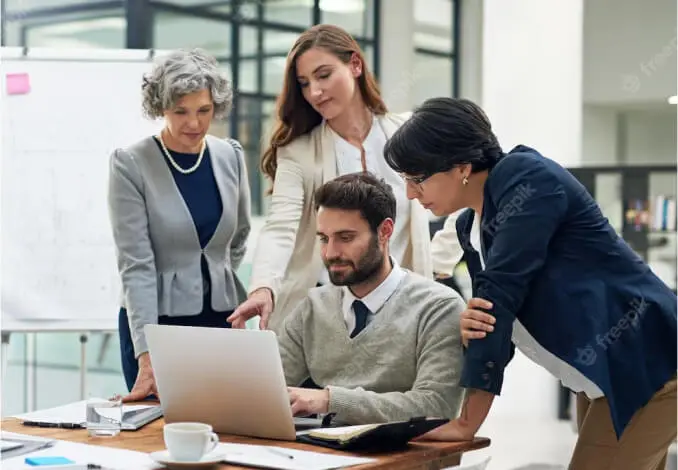 Des entrepreneurs collaborent autour d'un ordinateur pour créer une société de conseil dans un bureau moderne